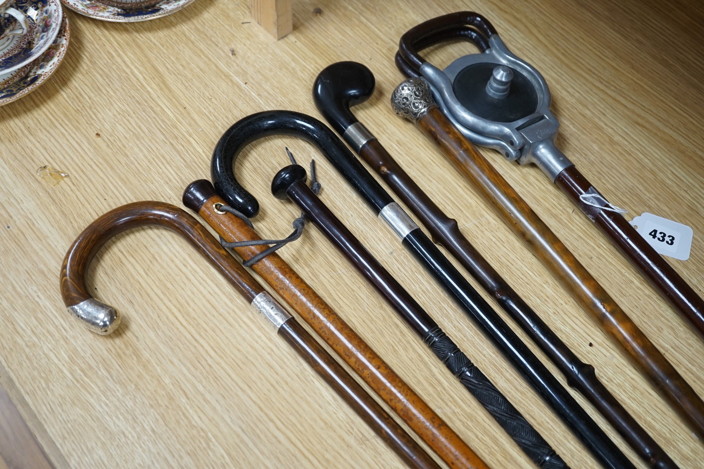 Four silver mounted walking canes, a malacca cane, a carved hardwood cane and a shooting stick (7)